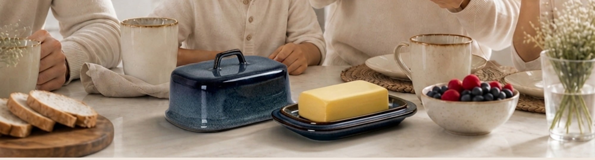 Mesa de desayuno familiar con la mantequillera SABN abierta, pan y un bol de fruta
